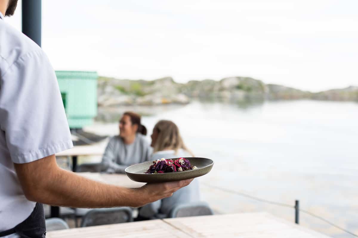 Servitris serverar mat på restaurang vatten vid havet